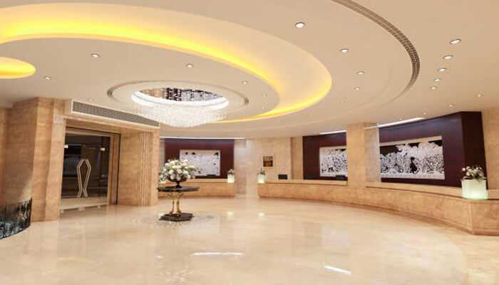 Spacious hotel lobby with polished beige floors and a striking circular ceiling design, offering a sleek, modern welcome in a refined setting.