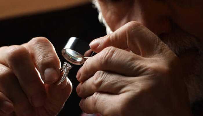 Experienced gemologist examining a diamond ring using a jeweler’s loupe for clarity and authenticity assessment.